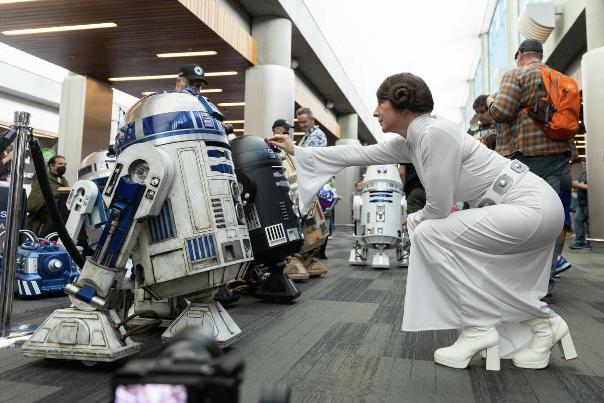 Sindiro Sheth, vestido como la Princesa Leia de "Star Wars", busca un robot R2-D2 de tamaño real en SiliCon con Adam Savage en el Centro de Convenciones San Jose McEnery el 27 de agosto de 2022. 