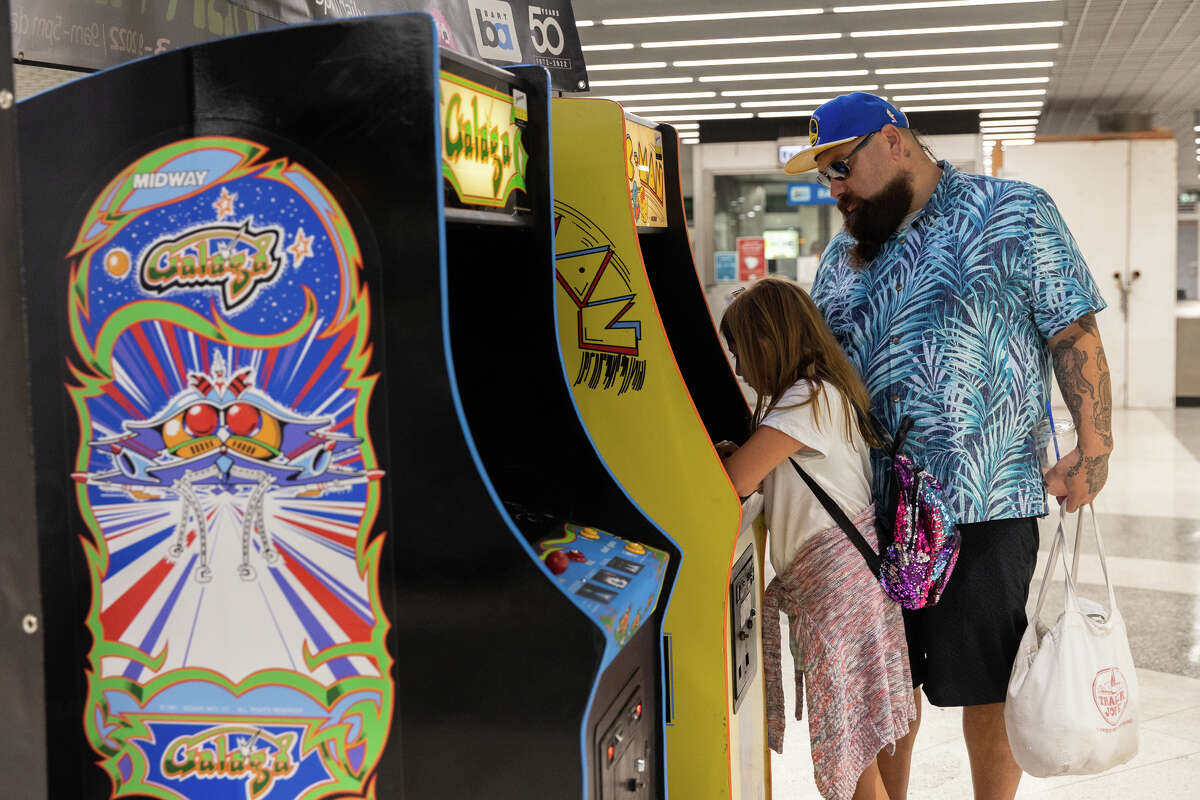 David Galdamez, a la derecha, y su hija, Abigail Galdamez, juegan Pac-Man en una máquina recreativa antigua en la estación BART de Powell Street en San Francisco el 3 de septiembre de 2022. 