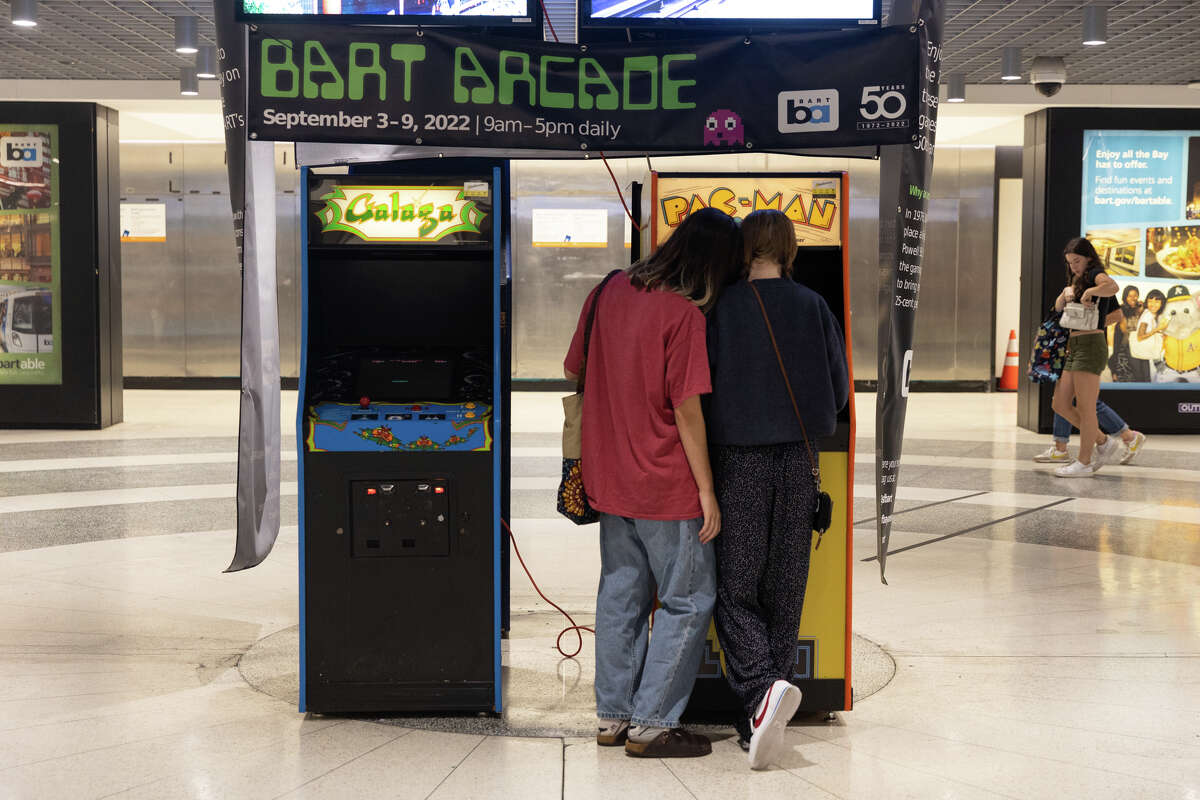La gente juega en máquinas recreativas antiguas en la estación BART de Powell Street en San Francisco el 3 de septiembre de 2022. 