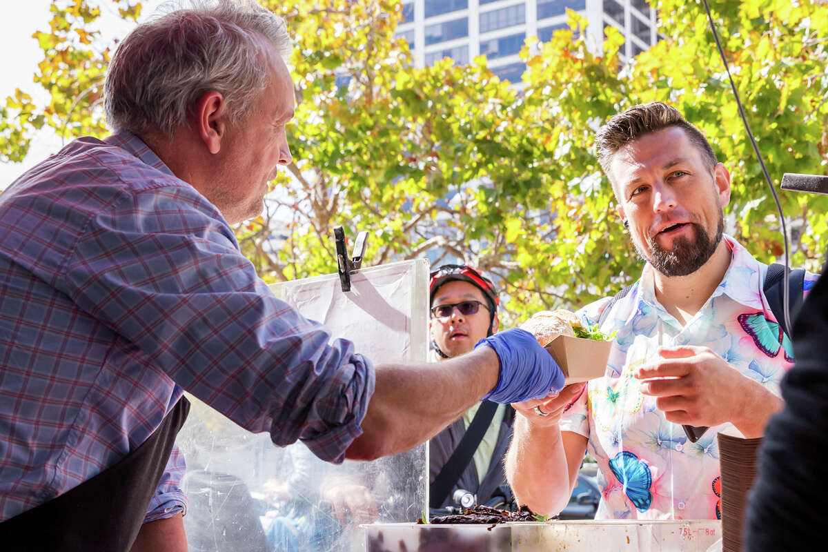 Thomas Odermatt entregando un sándwich de porchetta a un cliente en el camión de comida Roli Roti en el Ferry Building en San Francisco, California, el 20 de septiembre de 2022.