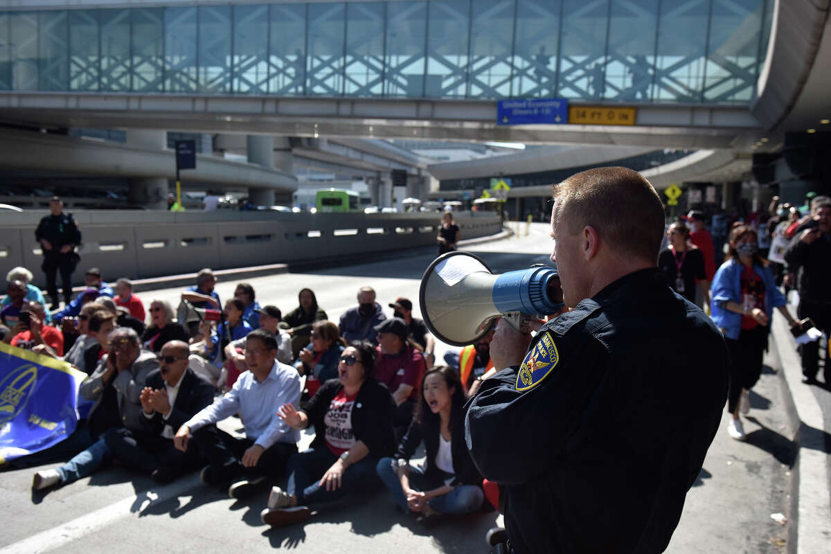 Un oficial del SFPD se dirige a los trabajadores del sindicato UNITE HERE Local 2 mientras bloquean el tráfico en la Terminal 3 durante una manifestación por mejoras en los contratos, el viernes 16 de septiembre de 2022. 