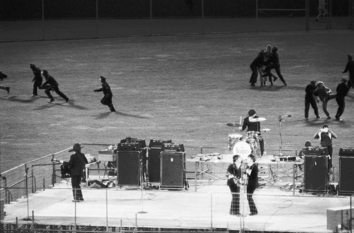 La policía despeja el campo de fanáticos entusiastas mientras los Beatles actúan en un quiosco de música en Candlestick Park, San Francisco.