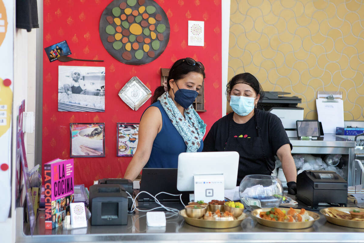 De izquierda a derecha, Sunita Pradhan Giri (hermana de Binita) y Gita Pradhananga hablan sobre un pedido detrás del mostrador en Bini's Kitchen en San Francisco el 23 de septiembre de 2022.