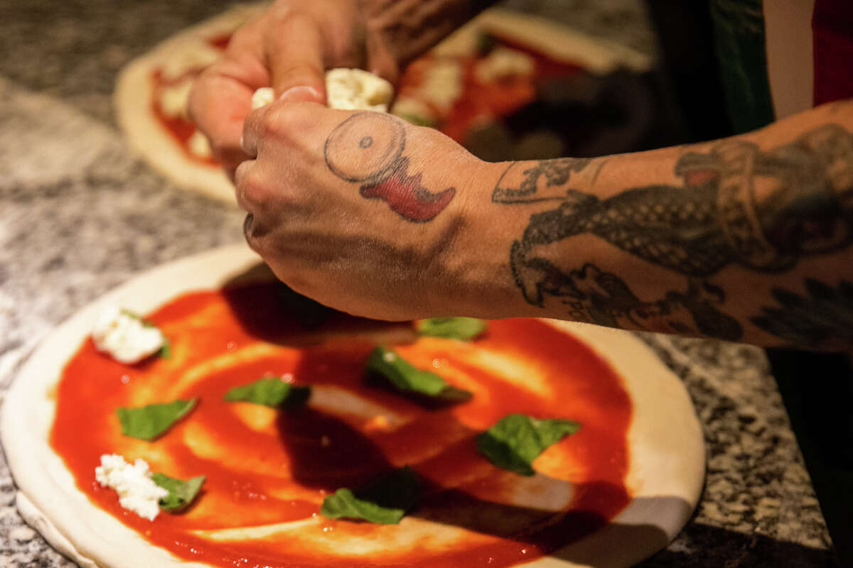 Un tatuaje de un cortador de rebanadas de pizza está en la mano del propietario Tony Gemignani que hace pizzas en Tony's Pizza Napoletana en San Francisco, California, el 18 de octubre de 2022. Gemignani fue reconocido recientemente en una competencia de mejor pizza del mundo.