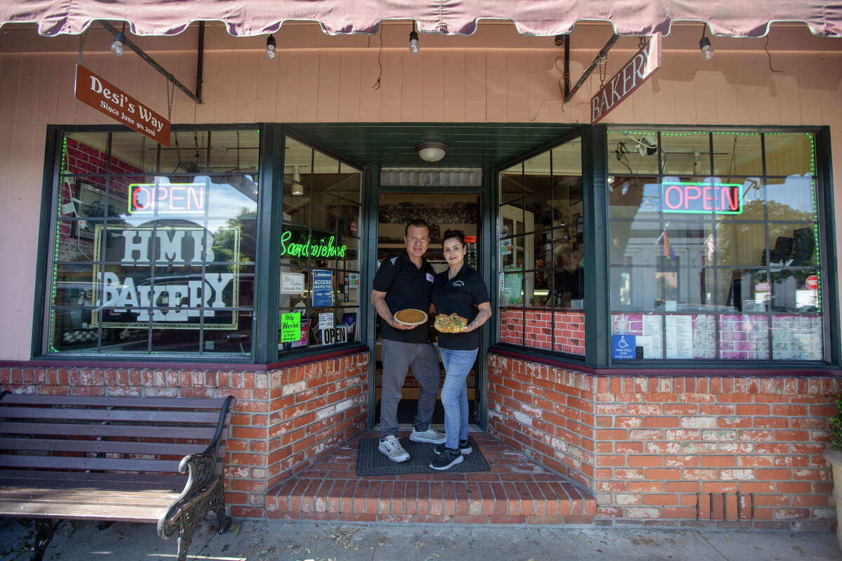 Los propietarios Desi y Blanca Sánchez se paran en la entrada de Half Moon Bay Bakery en Half Moon Bay, California, el 19 de octubre de 2022.