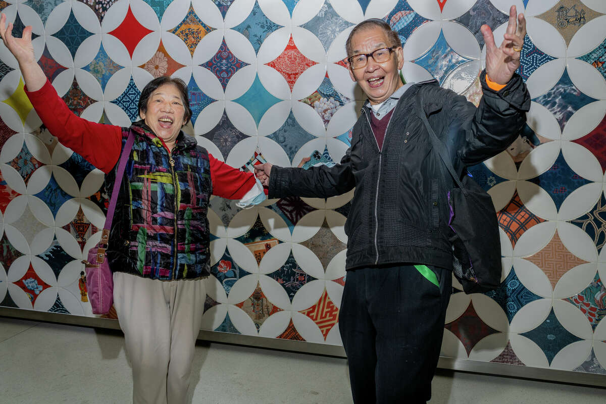 Yihung Wong y su esposo John de San Francisco celebran frente a la obra de arte "A Sense of Community" de Clare Rojas en la estación Chinatown Rose Pak el jueves 20 de octubre de 2022.