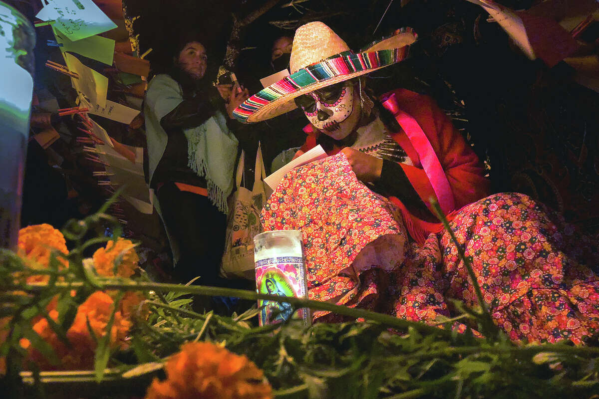 Una mujer escribe un mensaje al difunto al final de la celebración del Día de Muertos en un altar en el Parque Potrero del Sol de San Francisco el miércoles por la noche.