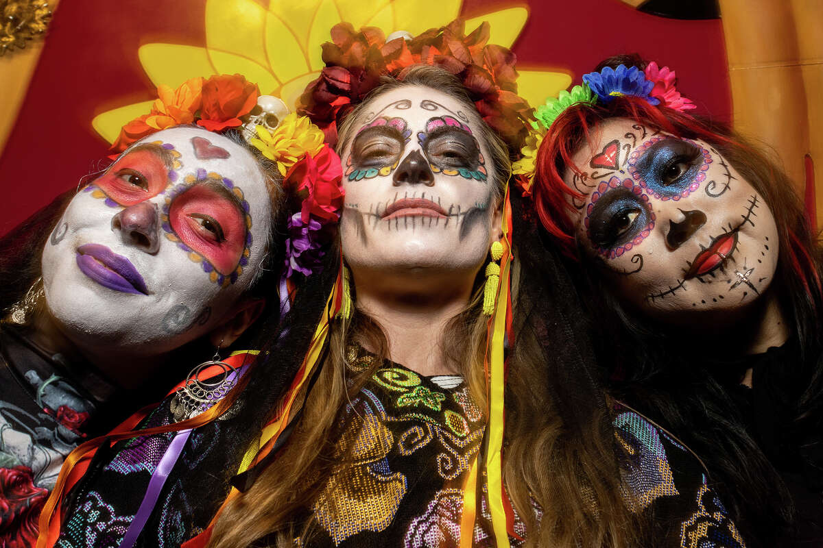 Valerie Medina, Michelle Lovick y Mishi Chan, todos de San Francisco, presentan sus respetos a los muertos en el Balmy Alley del Distrito de la Misión durante la celebración del Día de los Muertos en San Francisco el miércoles por la noche.