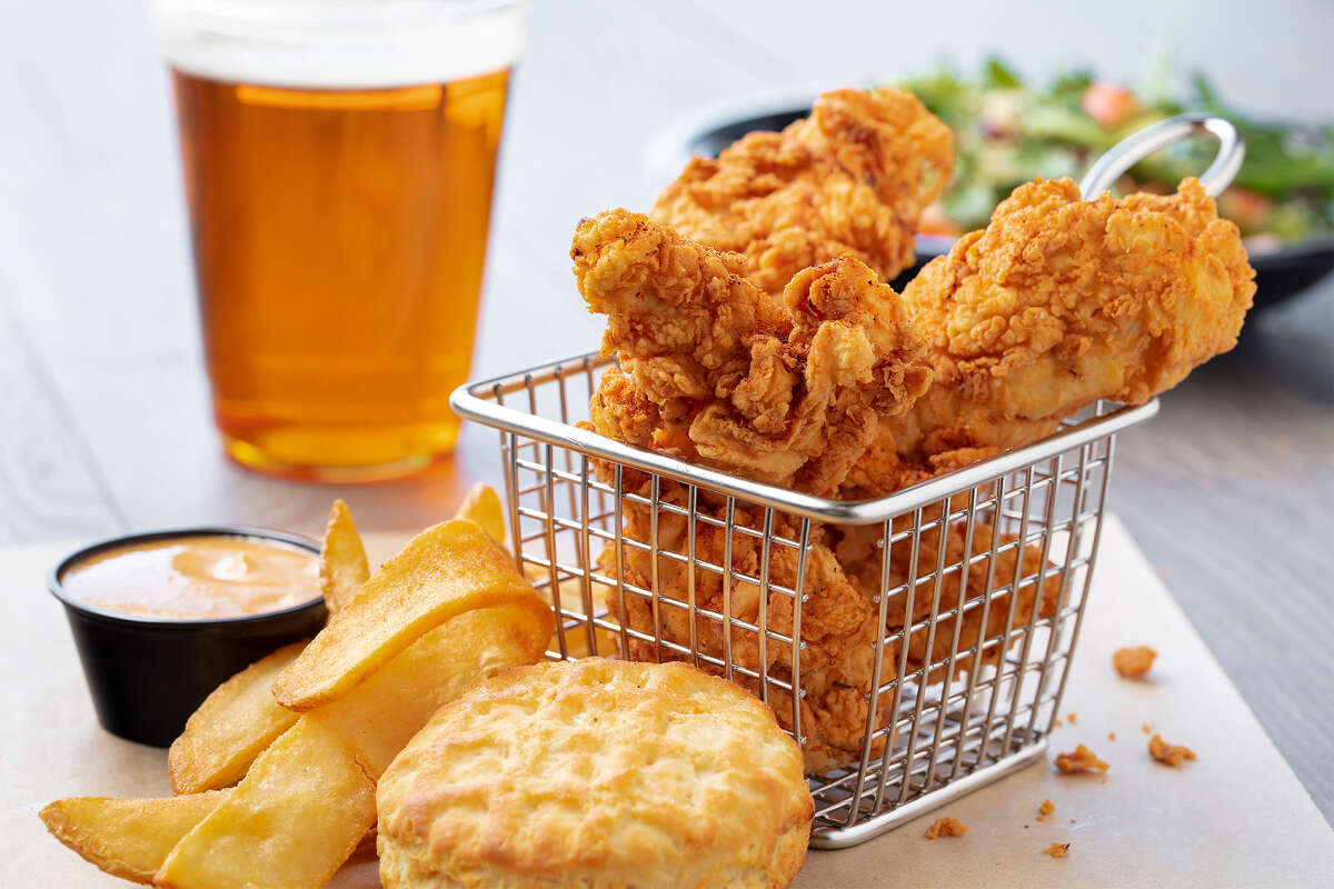 Tiras de pollo frito sureño con papas fritas planas, galleta waffle y salsa cajún en EddieWorld en Yermo, CA