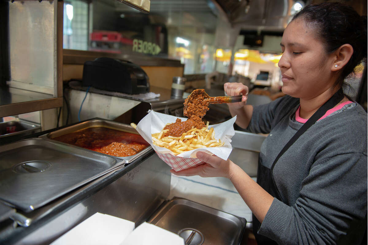 Un miembro del personal de Willie's sirve chili sobre papas fritas en Willie's Burgers en Sacramento, California, el 20 de noviembre de 2022.