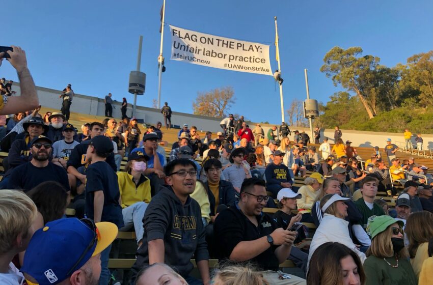  Manifestantes vestidos como árbitros muestran pancartas durante el partido de fútbol de California