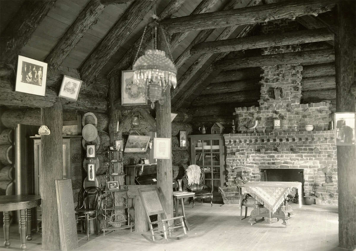 Vista interior de Pioneer Log Cabin, con vista a la chimenea de ladrillo, fecha desconocida. 