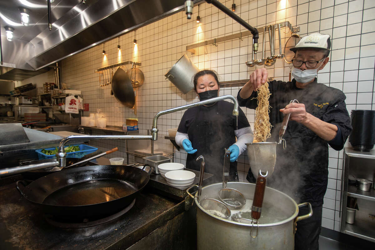 (De izquierda a derecha) El chef Yang y el chef Fung preparan una sopa wonton de fideos en el mercado nocturno en el sur de San Francisco, California, el 10 de noviembre de 2022.