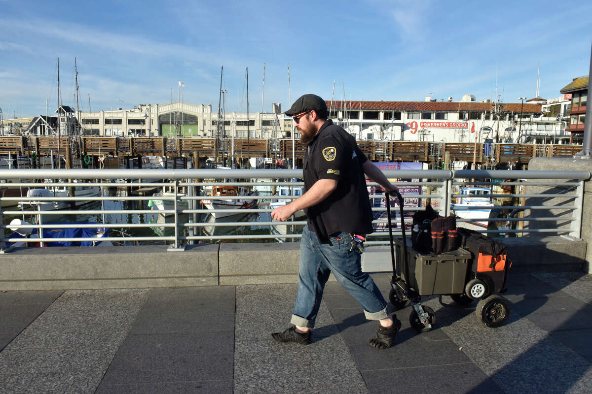 Matthew Sengbusch camina por Fisherman's Wharf durante sus rondas mensuales para dar servicio a varias prensas de centavo en el área, el martes 22 de noviembre de 2022.