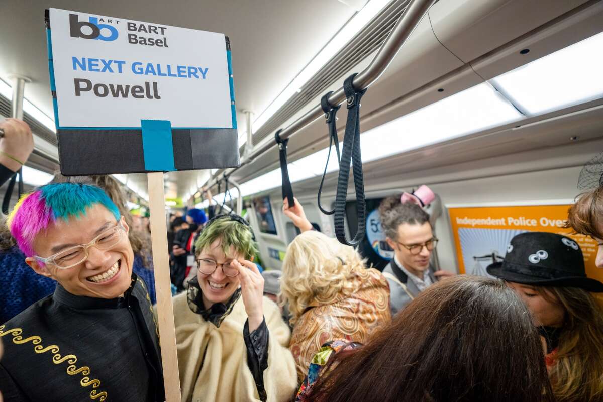 Un voluntario en la exhibición de arte BART Basel 2022 lleva un cartel para ayudar a los asistentes a dirigirse a la estación Powell BART en el centro de San Francisco el sábado 3 de diciembre de 2022.