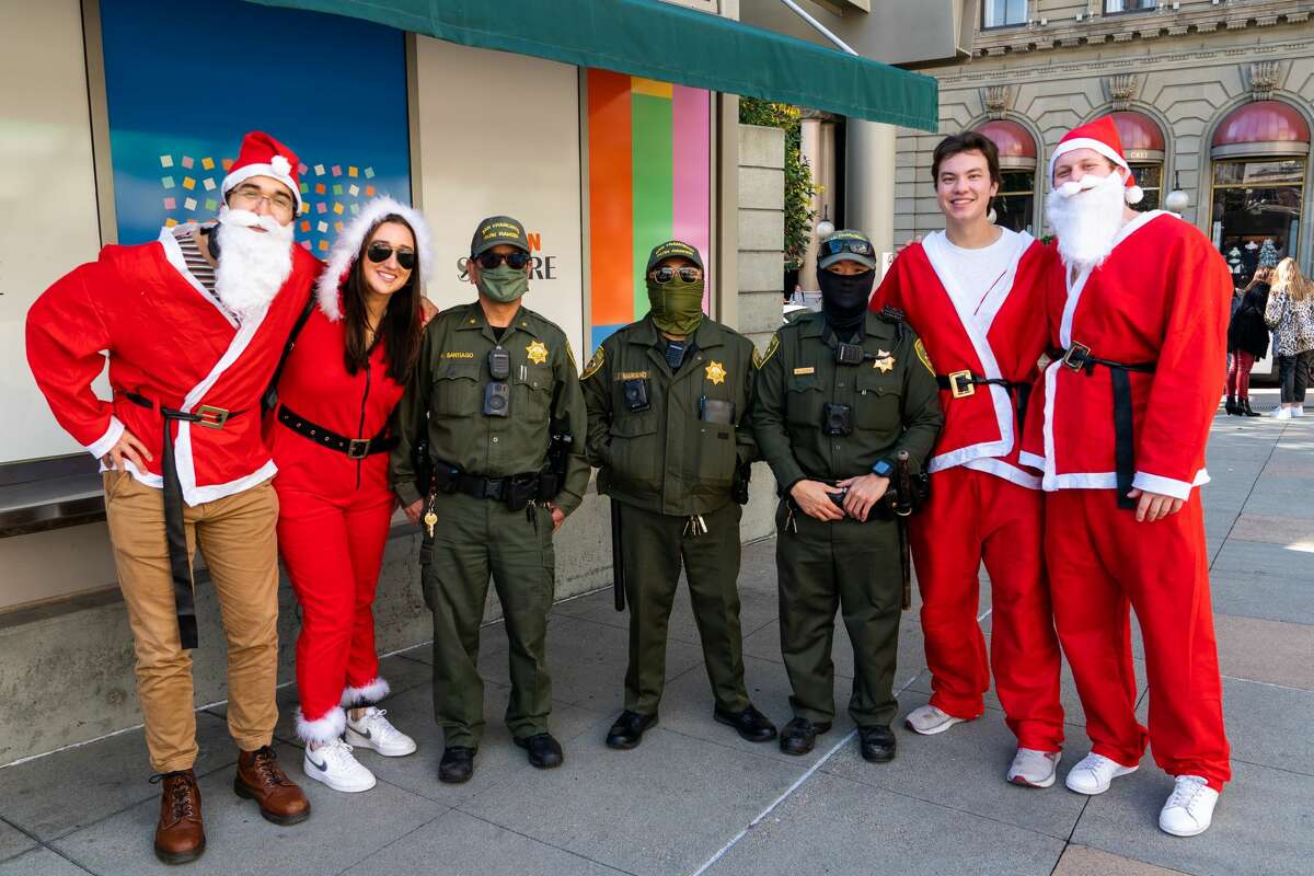 El editor de política de SFGATE, Eric Ting, posa con amigos y guardaparques de San Francisco en SantaCon en Union Square de San Francisco el 11 de diciembre de 2021.