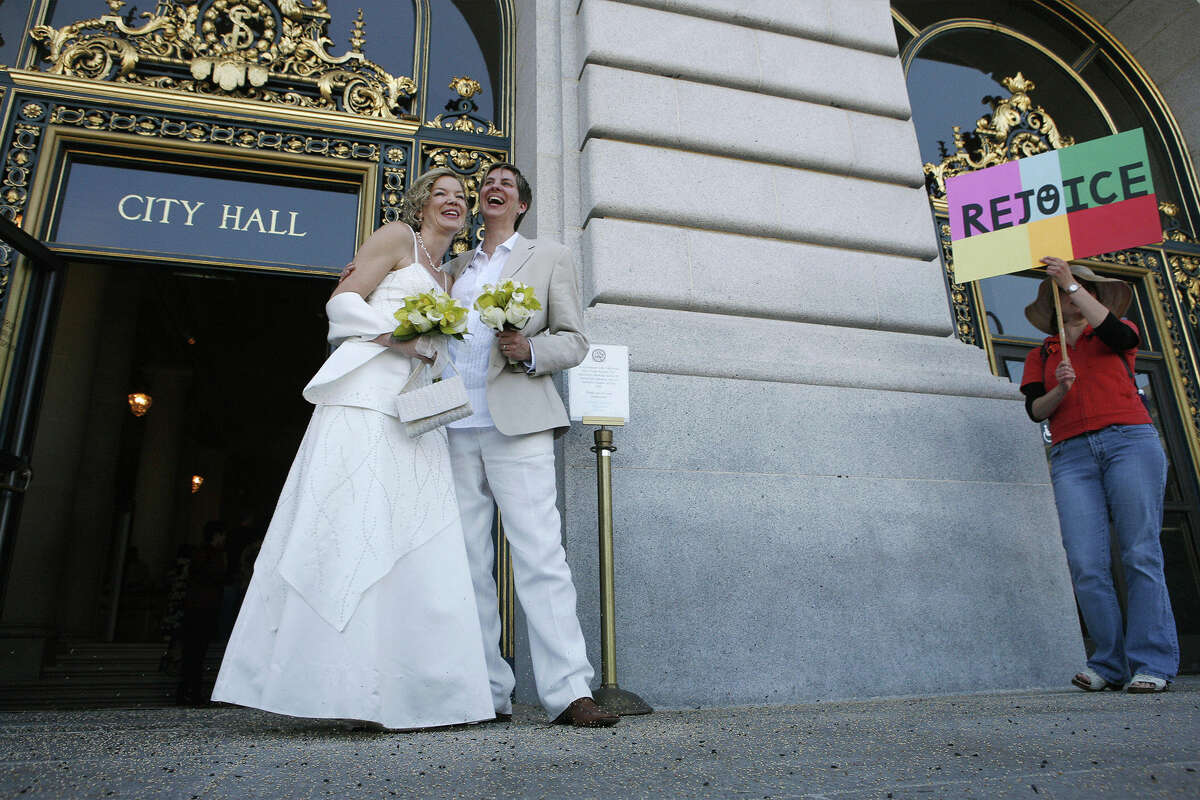 con sus letras doradas "ventana de la boda," El trabajo de Vigeant se puede ver en cientos, si no miles, de fotos de bodas. Tara Walsh, a la izquierda, y Wen Minkoft saludan a la multitud antes de dirigirse al Ayuntamiento para intercambiar votos en San Francisco, CA, el martes 17 de junio de 2008.