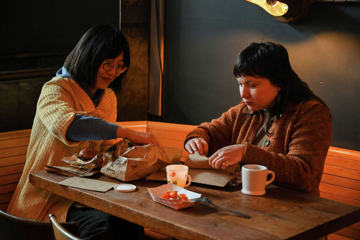 Catherine Pyun y Brianna Meli (de izquierda a derecha) se sientan dentro del restaurante emergente Egg Pals de Ramen Shop en Oakland, California, el domingo 18 de diciembre de 2022. Ambas ordenaron arenas de tocino, un limpiador de paladar (plato de fruta) y cafés.