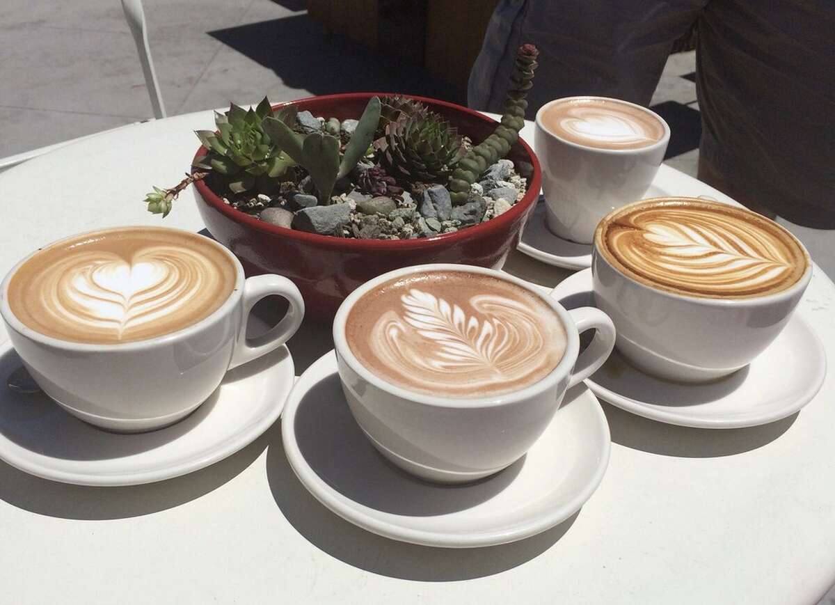 Cuatro cafés con leche con creativos diseños de espuma de Equator Coffees. 