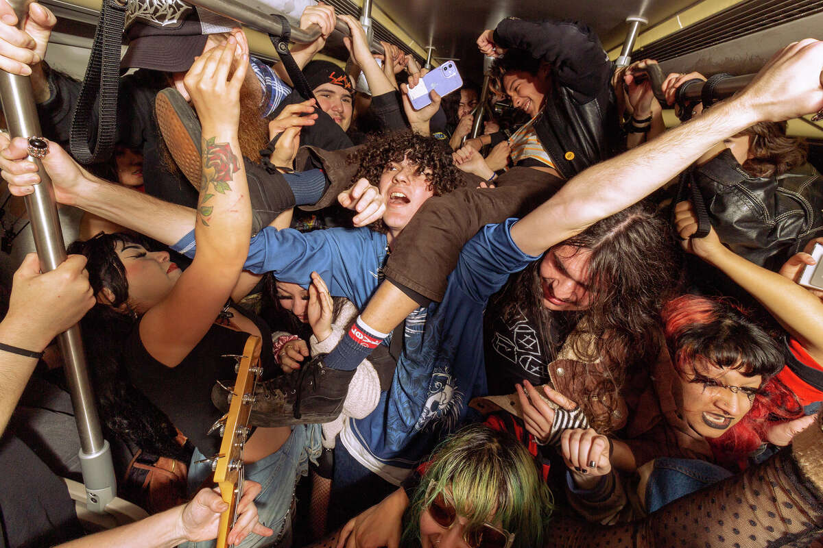 Los fanáticos reaccionan a un espectáculo en vivo de la banda local de punk rock False Flag dentro de un tren BART que se dirige al oeste hacia San Francisco, el viernes 6 de enero de 2023.