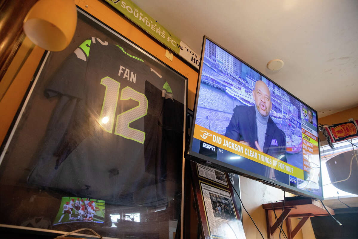 Una camiseta comprada por los fanáticos de los Seattle Seahawks que se reúnen para ver los partidos en Danny Coyle's adorna la pared del bar junto a un televisor que también compraron para ver los partidos en San Francisco el 13 de enero. Danny Coyle's es un hogar lejos del hogar para los Seahawks aficionados a ver los partidos.