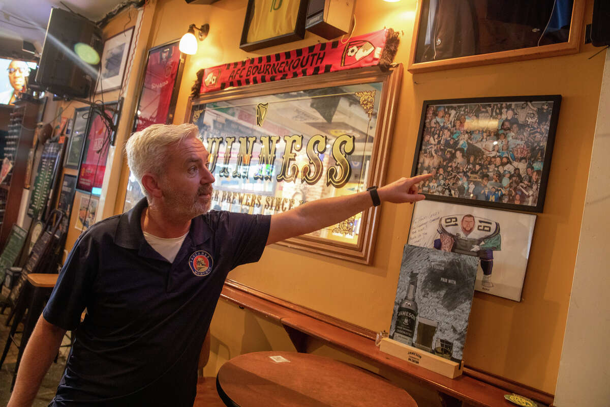 Brian Coyle, propietario de Danny Coyles, señala un collage de fanáticos de Los Angeles Chargers que vieron partidos en su bar en Haight Street en San Francisco, California, el 13 de enero de 2023.