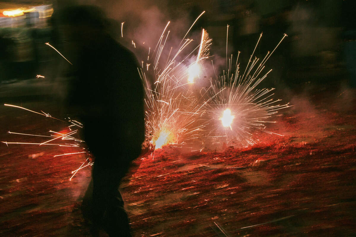 Un hombre camina junto a los fuegos artificiales en vivo en Grant Avenue durante las celebraciones del Año Nuevo Lunar en Chinatown el sábado 21 de enero de 2023 por la noche.