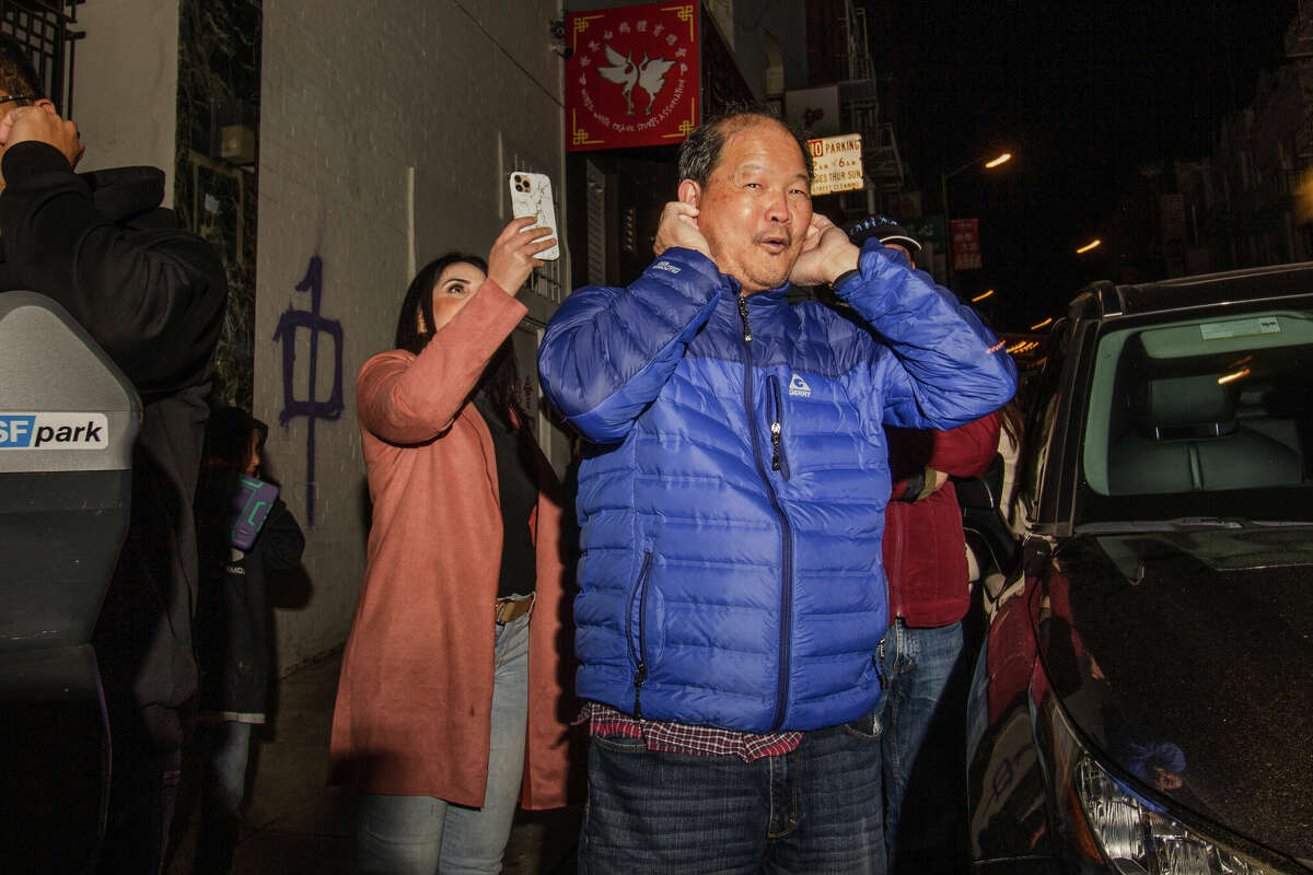 Un juerguista se tapa los oídos a lo largo de Jackson Street durante las celebraciones del Año Nuevo Lunar en Chinatown el sábado 21 de enero de 2023 por la noche.
