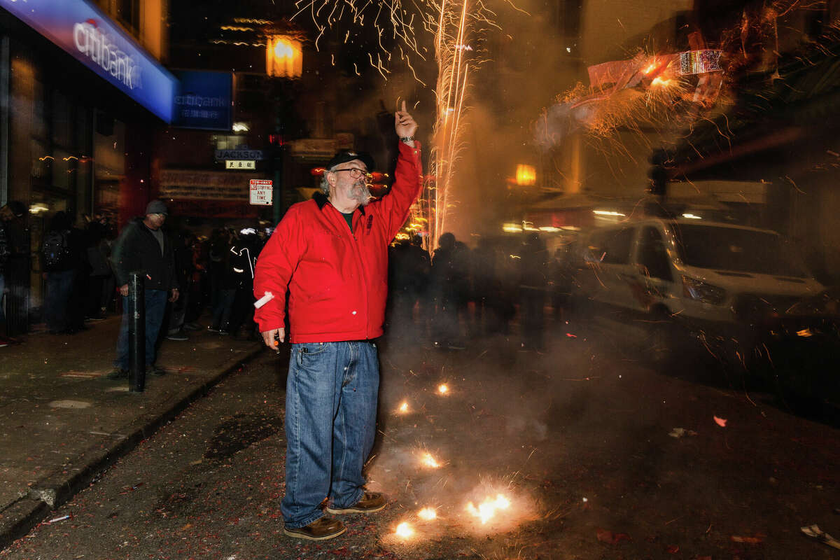 Un asistente al evento apunta hacia el brillante cielo nocturno en Grant Avenue durante las celebraciones del Año Nuevo Lunar en Chinatown el sábado 21 de enero de 2023 por la noche.