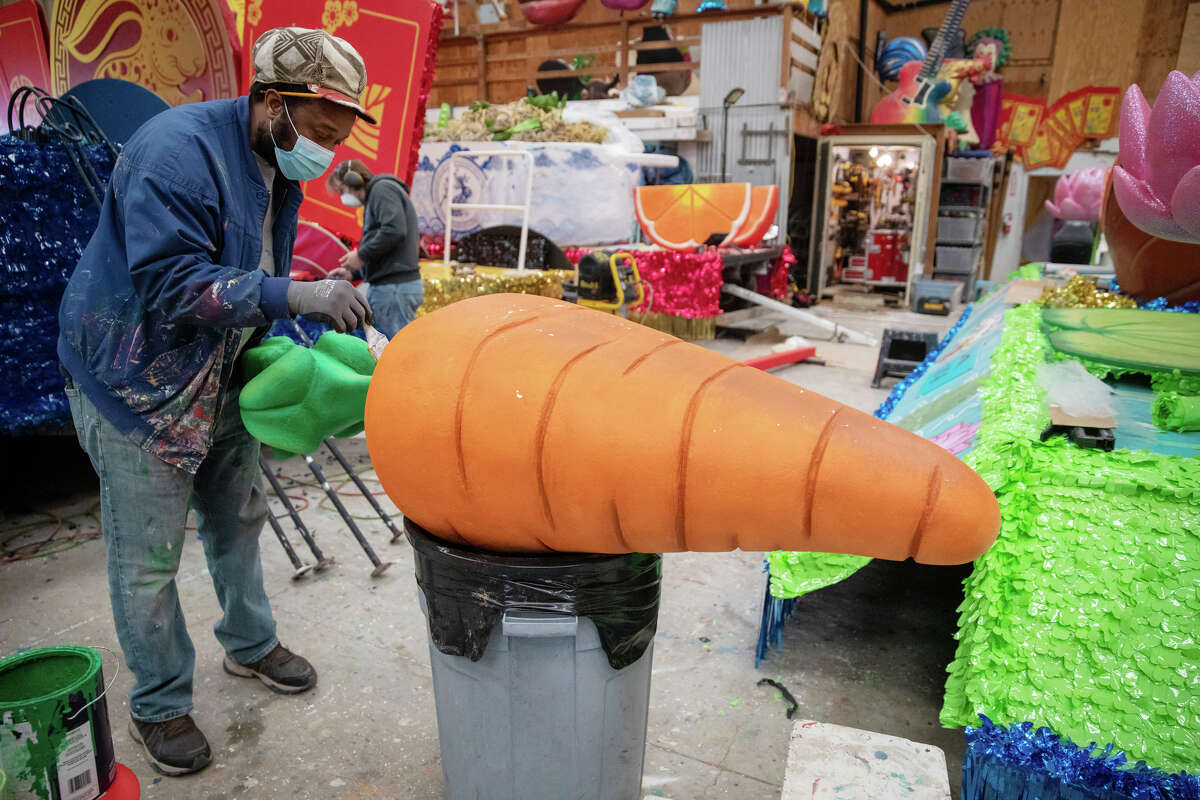 Un trabajador pinta una zanahoria gigante mientras trabaja en los artículos que aparecerán en las carrozas del desfile que participarán en el Desfile de Chinatown en un almacén en el Muelle 54 en San Francisco, California, el 30 de enero de 2023.