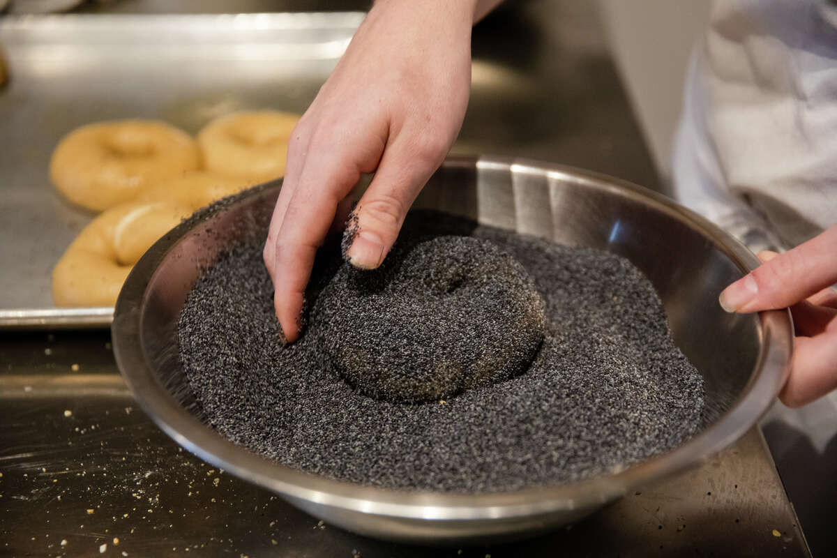 Un bagel está completamente cubierto con semillas de amapola después de hervirlo y antes de hornearlo el día de la inauguración de Poppy Bagels en Oakland, California, el 2 de febrero de 2023.