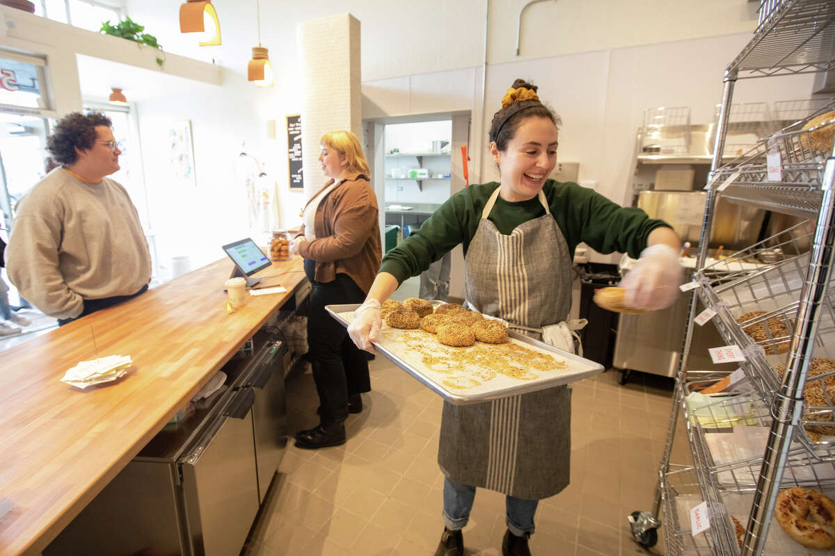 La propietaria Reesa Kashuk coloca algunos bagels recién horneados en canastas para venderlos durante el día de apertura de Poppy Bagels en Oakland, California, el 2 de febrero de 2023.