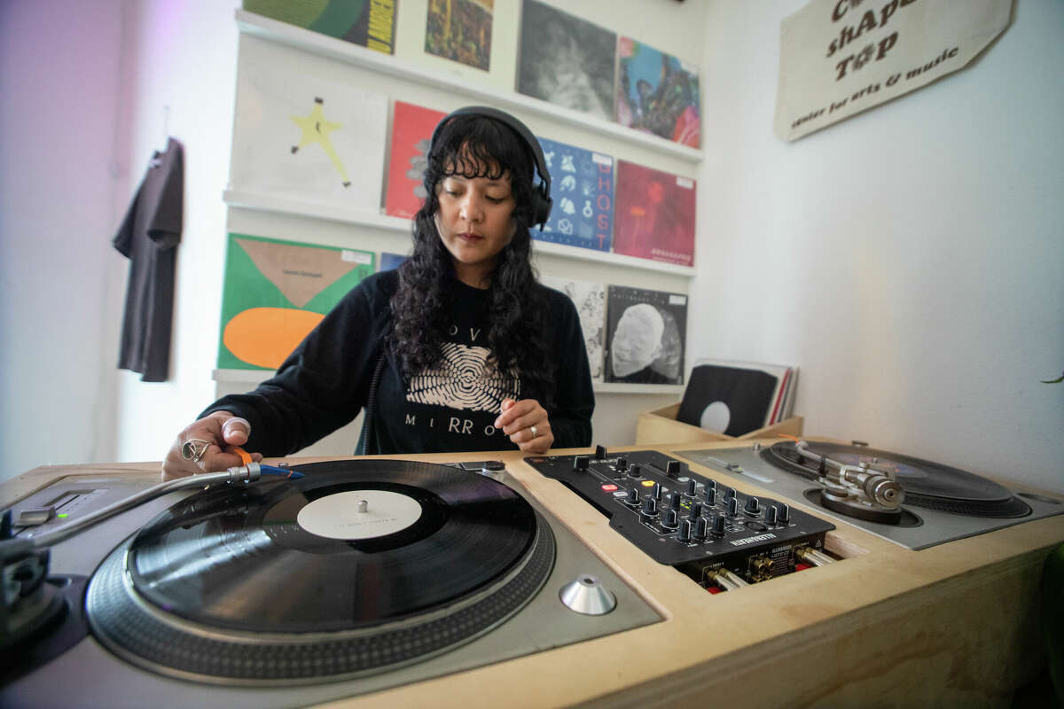 Cat Lauigan mezcla algunos discos en una estación de mezclas de DJ de vinilo en la tienda de discos Cone Shape Top en Oakland, California, el 14 de febrero de 2023.