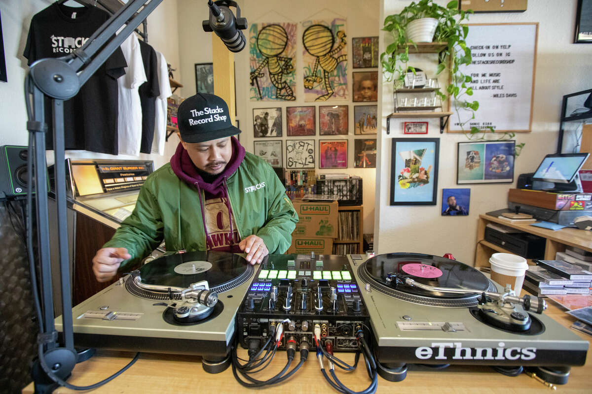 El propietario Gabe Dela Cruz toca algunos discos en su estación de DJ dentro de The Stacks Record Shop en Hayward, California, el 14 de febrero de 2023.