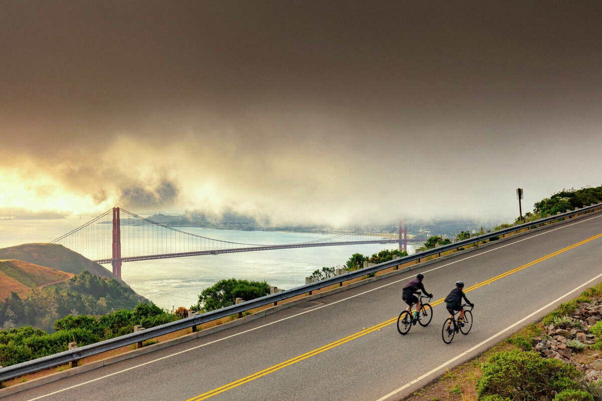 Dos ciclistas dan un paseo con el puente Golden Gate y San Francisco al fondo.