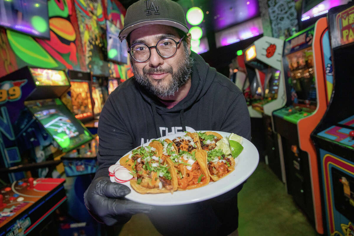 El propietario Raúl Medina sostiene un plato de sus tacos veganos de La Venganza dentro de Emporium Arcade Bar en Oakland, California, el 9 de marzo de 2023.