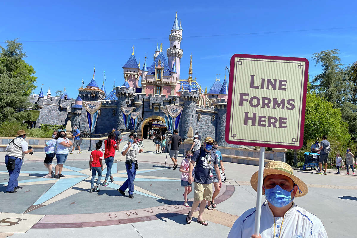 Un empleado de Disneyland forma una fila para que los visitantes tomen fotografías frente al Castillo de la Bella Durmiente en Anaheim, California, el 30 de abril de 2021. 