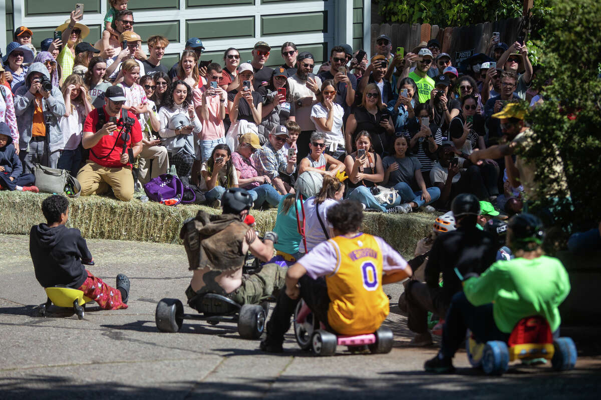 Los espectadores ven a los corredores tomar una curva durante el evento de carreras Bring Your Own Big Wheels en Vermont Street en San Francisco, California, el 9 de abril de 2023.