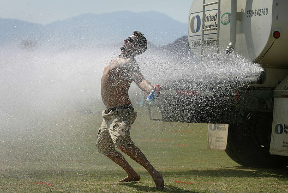 ARCHIVO: Combatiendo el calor el jueves antes del Festival de Música y Artes de Coachella Valley, Tony Lynch, de 24 años, de Albany, Nueva York, se refresca detrás de un camión cisterna después de instalar su campamento el 26 de abril de 2007.