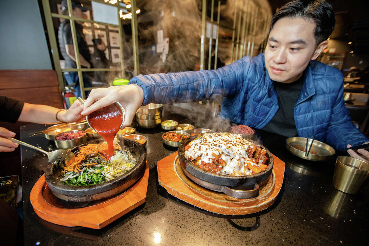 Tim Cheung de Bay Area Foodies vierte un poco de gochujang en un plato de bibimbap en Daeho Kalbijjim & Beef Soup en San Francisco el 9 de mayo de 2023. Es una persona influyente en las redes sociales con cientos de miles de seguidores en Instagram y TikTok.