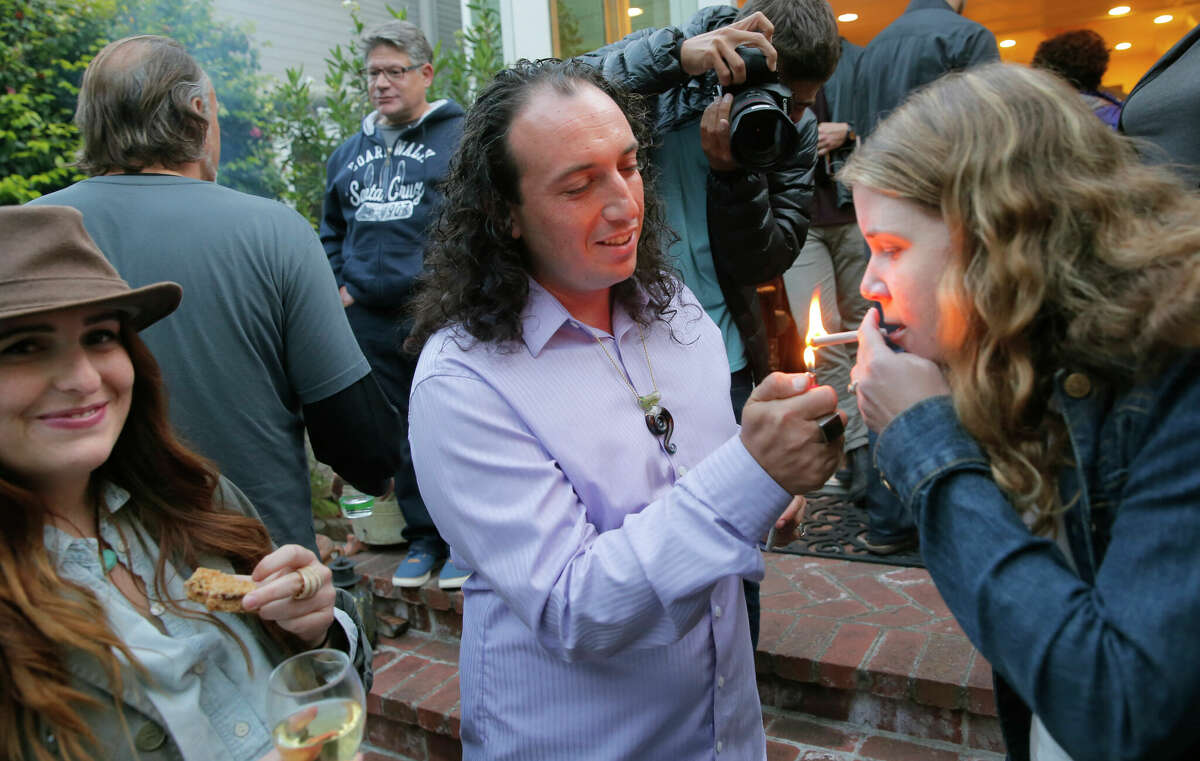 Nicholas Cashmere enciende un porro para Ellen Holland, ambos de Oakland, en un evento de muestreo de comida y hierba en una casa de Cole Valley en San Francisco, California, como se vio el jueves. 11 de junio de 2015. 