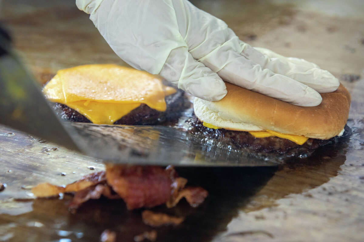 Alma Gutiérrez termina de cocinar una hamburguesa con queso en la parrilla plana de Bud's Giant Burgers en Vallejo, California, el 24 de mayo de 2023.