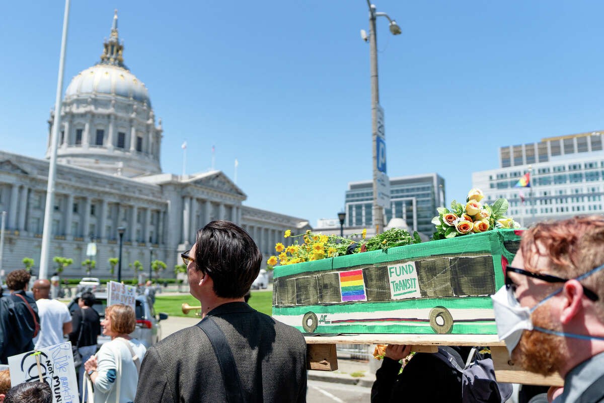 Una multitud de asistentes al Funeral de Tránsito y partidarios de la financiación del transporte público marchan frente al ayuntamiento en el centro de San Francisco, California, el 3 de junio de 2023.