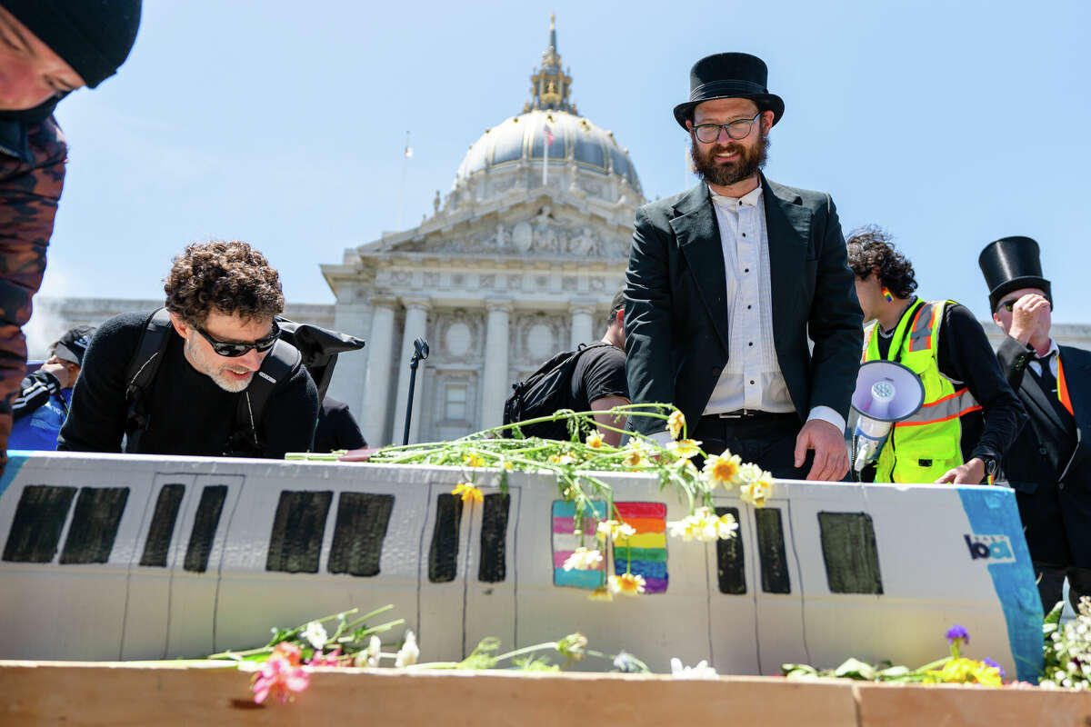 Los asistentes al funeral de tránsito y los partidarios de la financiación del transporte público depositan flores en el ataúd del automóvil BART frente al ayuntamiento en el centro de San Francisco, California, el 3 de junio de 2023.