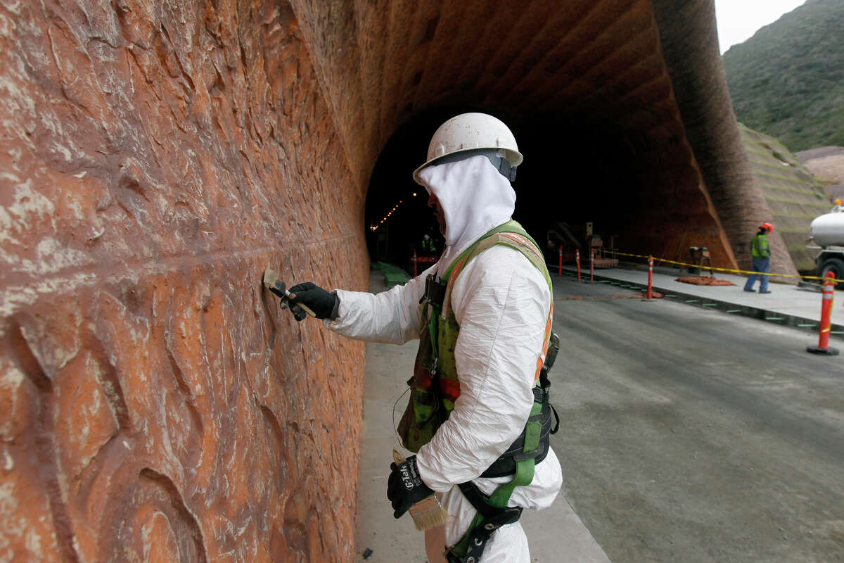 Un pintor retoca el muro de contención decorativo en el portal norte del proyecto del túnel Devil's Slide en Pacifica, California, el martes 31 de enero de 2012.