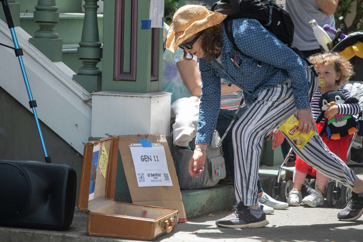 Un espectador da una propina a GEN11 mientras actúan en un escenario improvisado frente a una casa victoriana en 21st Street en Porchfest 2023, una fiesta comunitaria musical, en el Distrito de la Misión de San Francisco, California, el 10 de junio de 2023.