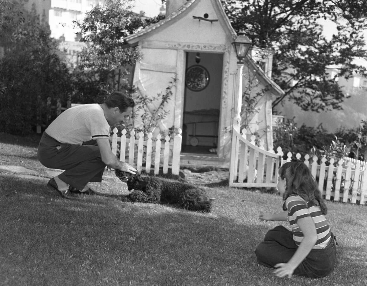 Walt Disney juega con su hija y su perro en su jardín alrededor de 1940 en Los Ángeles.