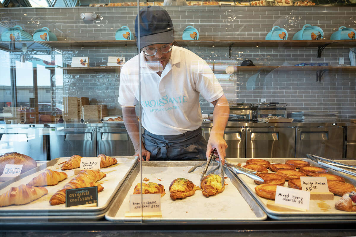 Hieu Tran agarra un croissant de jamón y queso para un cliente en Croissante en Santa Clara California, 20 de junio de 2023