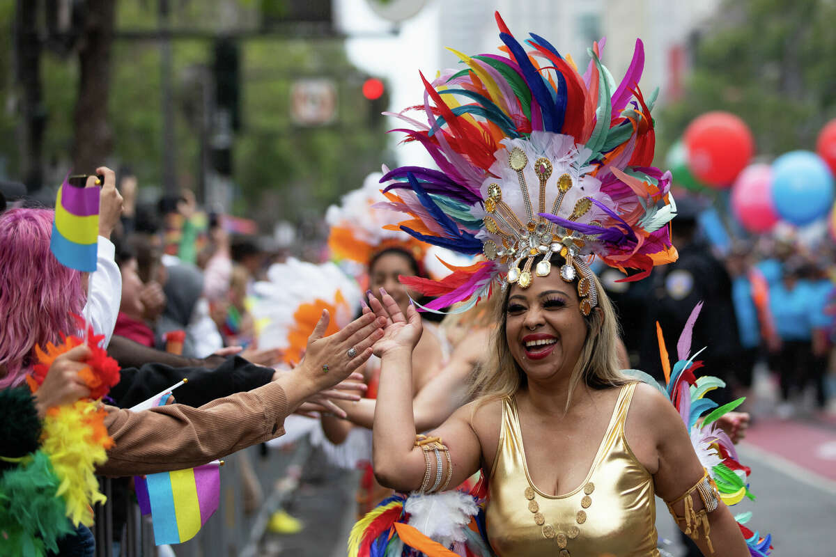 Una bailarina choca los cinco con los espectadores durante el Desfile del Orgullo Gay anual de San Francisco el 25 de junio de 2023. Foto de Magali Gauthier.