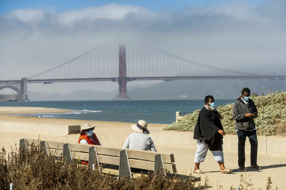 Con el puente Golden Gate de fondo, la gente pasea por Crissy Field East Beach en San Francisco. 